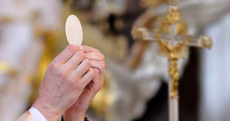 Priest raises host during Mass