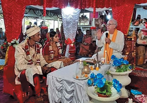 Groom, bride and Fr. Frank seated under the marriage canopy.