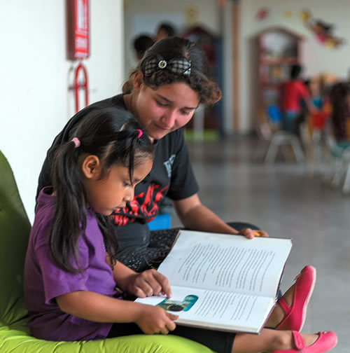 Volunteer tutors a child after school at Warmi Huasi