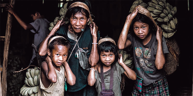 Hard-working mother and children carrying sacks of bananas