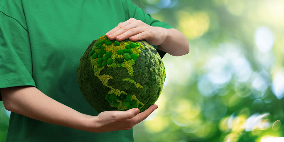 A person holds a green globe of the earth