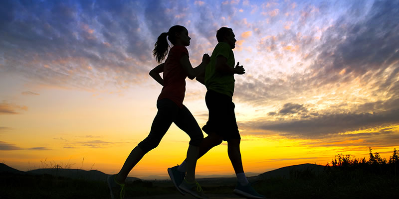 Two people running at sunset