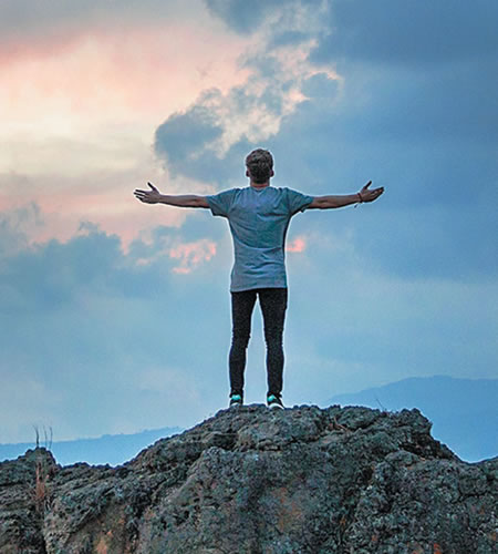 A Man arms outstreatch looking toward the sky in prayer