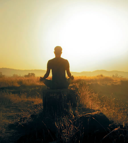 A man sitting on a tree stump in prayer