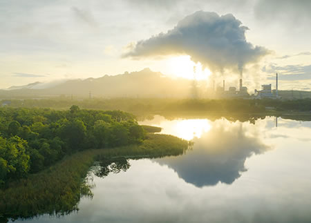 Coal power plant located along a winding scenic river belches smoke.