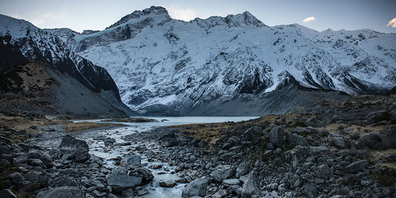 Snow-covered mountains with stream of glacial runoff.