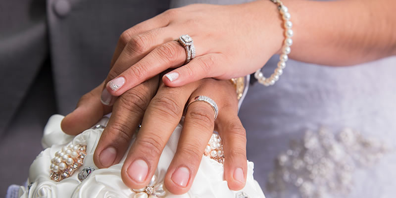 Married couple's hands clasped together showing wedding rings.