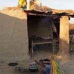 A girl spreads dried grass on the roof before plastering mud