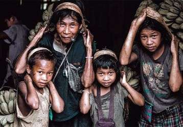 Hard-working mother and children carrying sacks of bananas