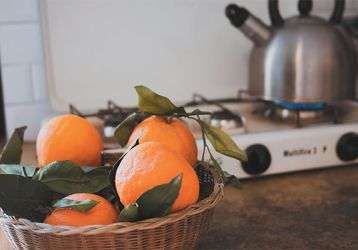 Basket of oranges and a teapot warming on the stove