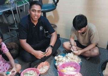 Columban student Matang Moeniba from Kiribati helping a family peel garlic for sale.