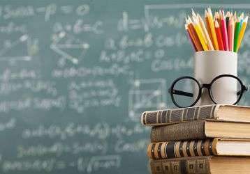 Stack of books and pencils in front of a blackboard 